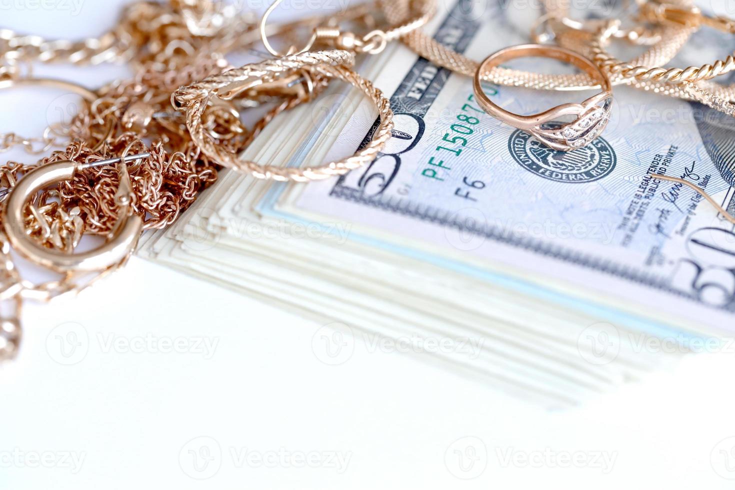 Many expensive golden jewerly rings, earrings and necklaces with big amount of US dollar bills on white background. Pawnshop or jewerly shop photo