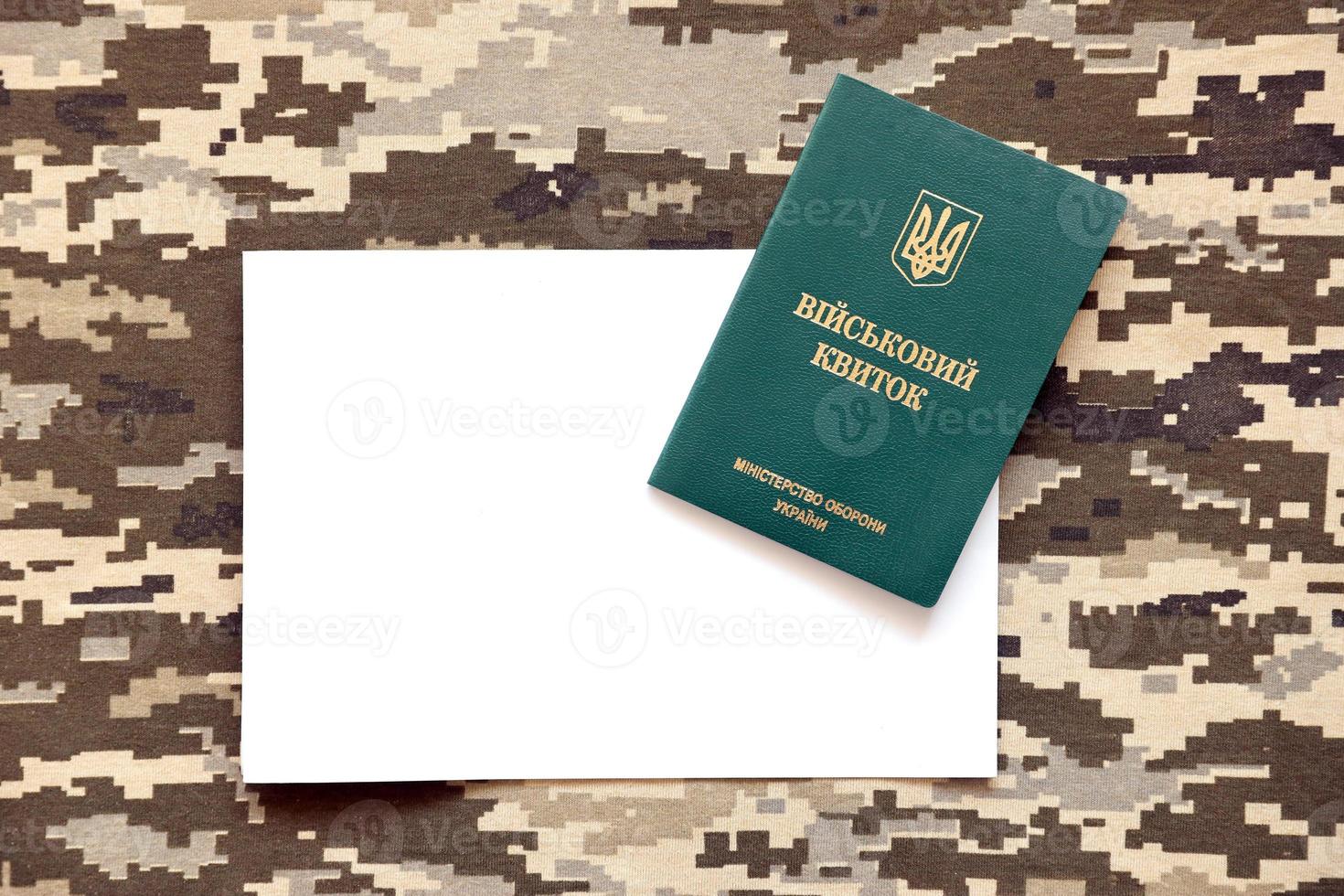 Ukrainian military ID and blank paper sheet on fabric with texture of pixeled camouflage. Cloth with camo pattern in grey, brown and green pixel shapes with Ukrainian army personal token. photo