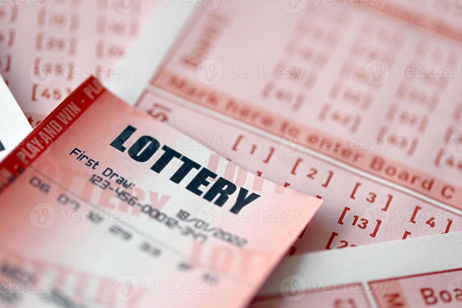 Red lottery ticket lies on pink gambling sheets with numbers for marking to play lottery. Lottery playing concept or gambling addiction. Close up photo