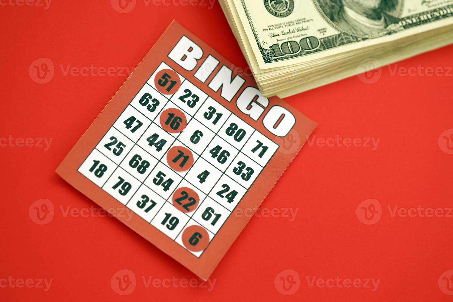 Red bingo board or playing card for winning chips and stack of dollar bills. Classic american or canadian five to five bingo card on red background photo