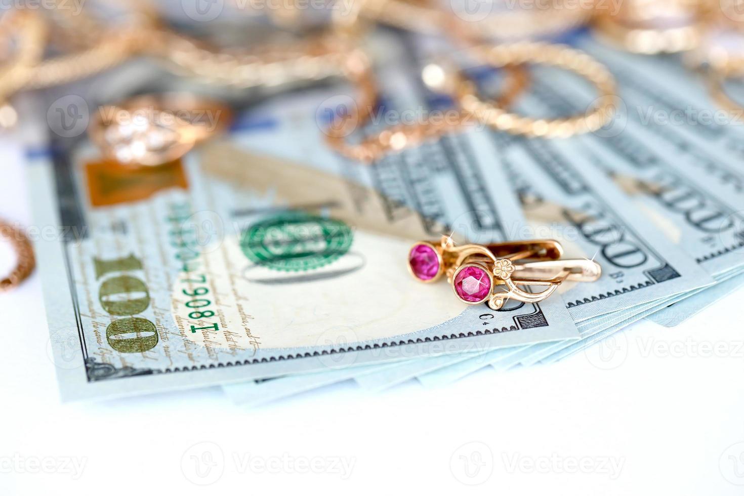 Many expensive golden jewerly rings, earrings and necklaces with big amount of US dollar bills on white background. Pawnshop or jewerly shop photo