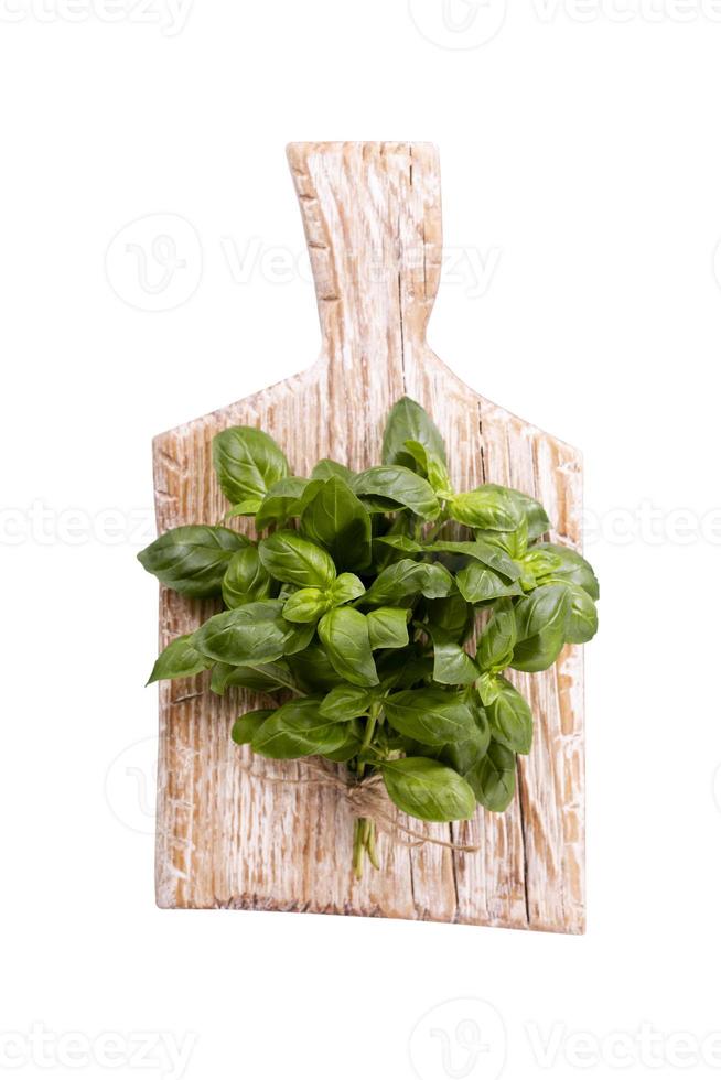 Bunch of fresh organic basil in cutting board on rustic wooden background photo