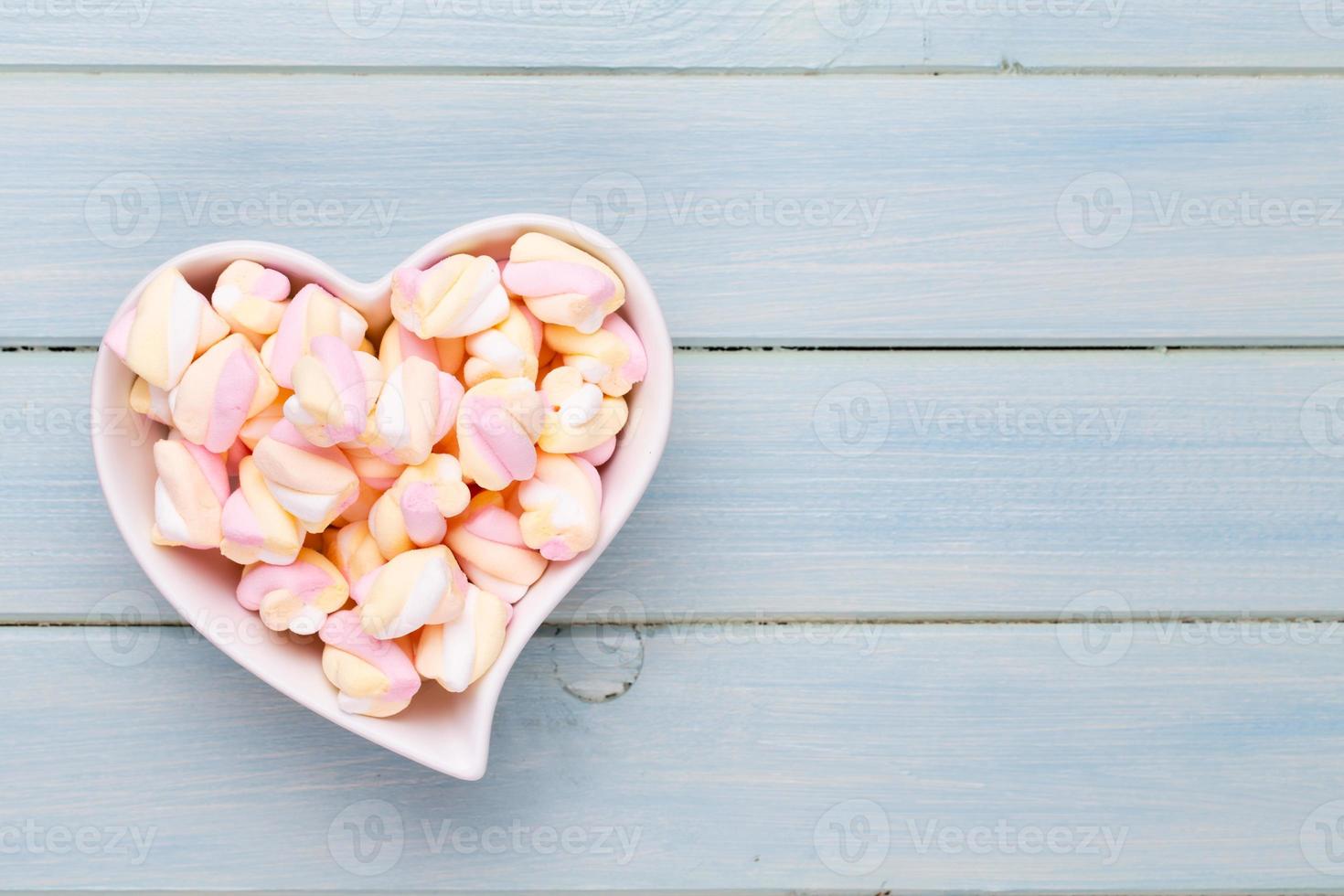 Marshmallows on blue background with copyspace. Flat lay or top view. Background or texture of colorful mini marshmallows. photo