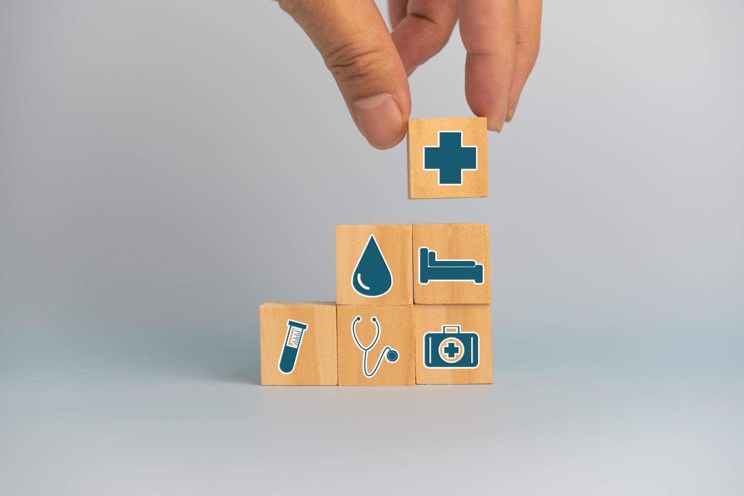 Hand holding wooden cubes block with insurance health car medical symbol on background and copy space. photo