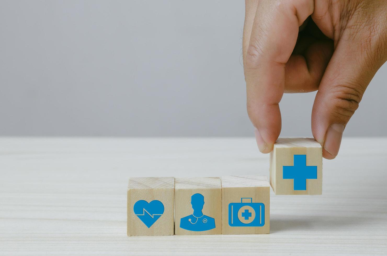 Hand holding wooden cubes block with insurance health car medical symbol on background and copy space. photo