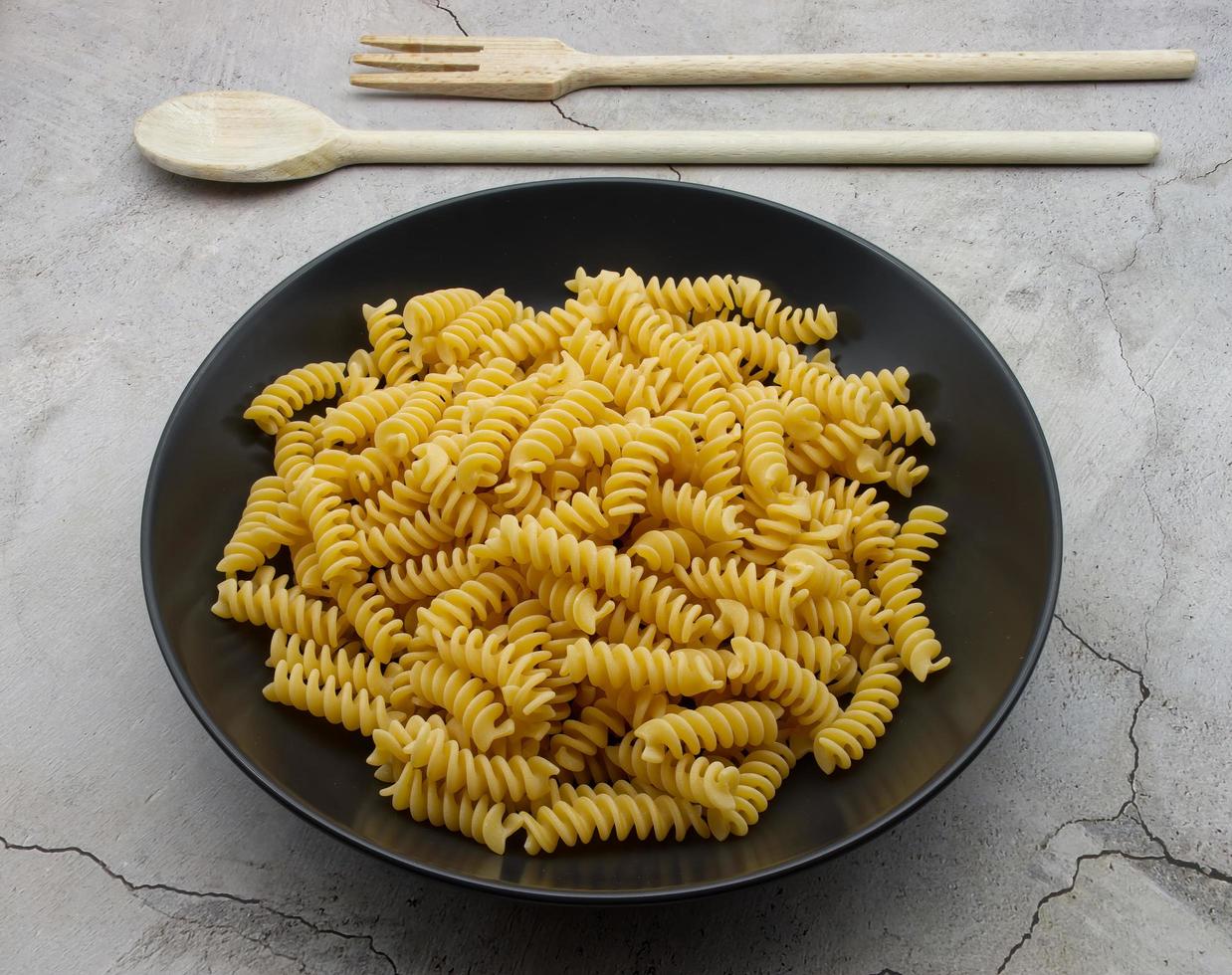 Raw Italian Fusilli Pasta in a black dish. Traditional Italian cuisine. photo