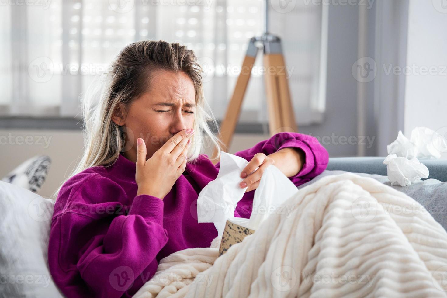 una mujer enferma y desesperada tiene gripe. rinitis, resfriado, enfermedad, concepto de alergia. una mujer bastante enferma tiene secreción nasal, se frota la nariz con un pañuelo. mujer estornudando. morena estornudando en un pañuelo foto
