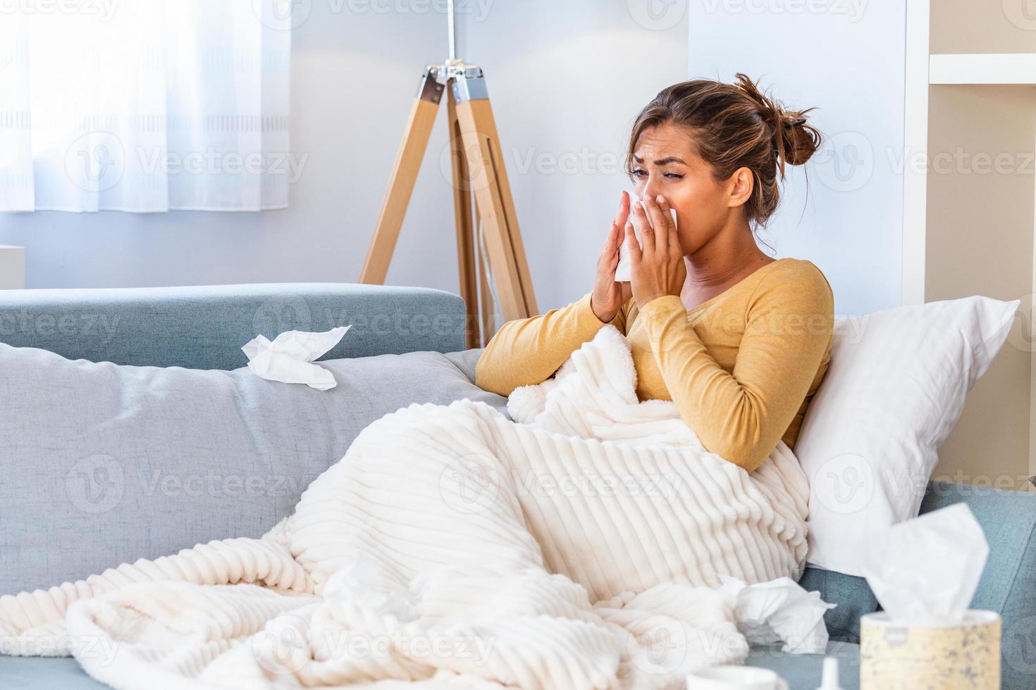 Sick Woman.Flu.Woman Caught Cold. Sneezing into Tissue. Headache. Virus .Medicines. Young Woman Infected With Cold Blowing Her Nose In Handkerchief. Sick woman with a headache sitting on a sofa photo