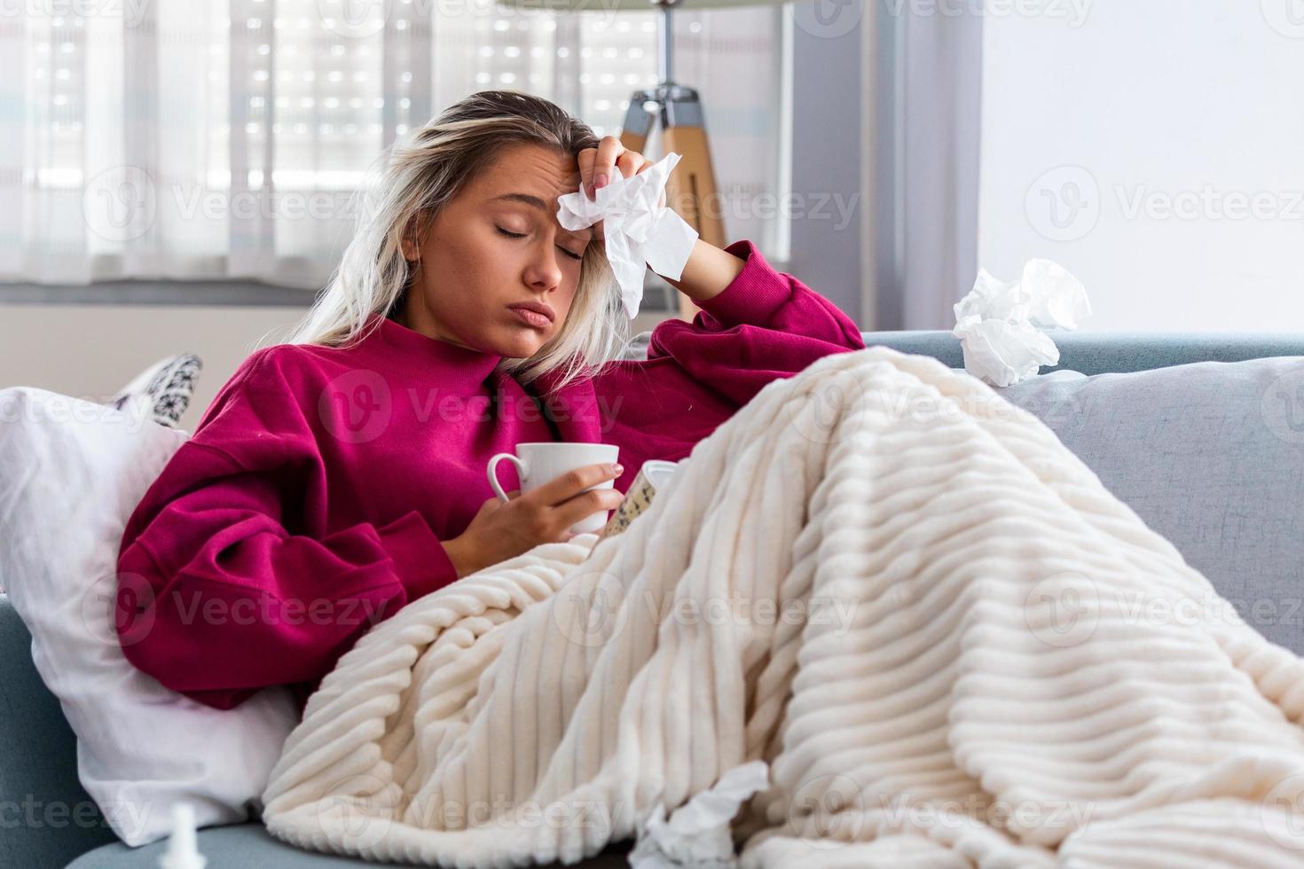 Woman Caught Cold having fever and Headache. Coronavirus symptoms . Young Woman Infected With Cold or COVID 19. Sick woman with a headache sitting on a sofa photo