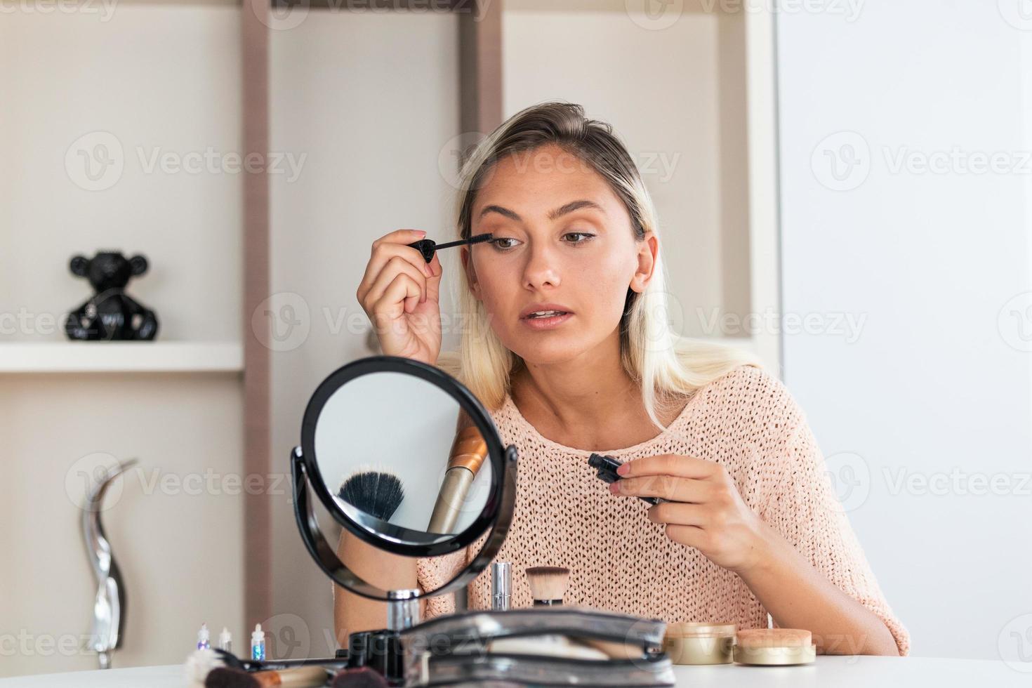 mujer aplicando rímel negro en las pestañas con pincel de maquillaje. maquillaje de belleza. retrato de una hermosa joven aplicando rímel negro en las pestañas, sosteniendo un cepillo en la mano. foto