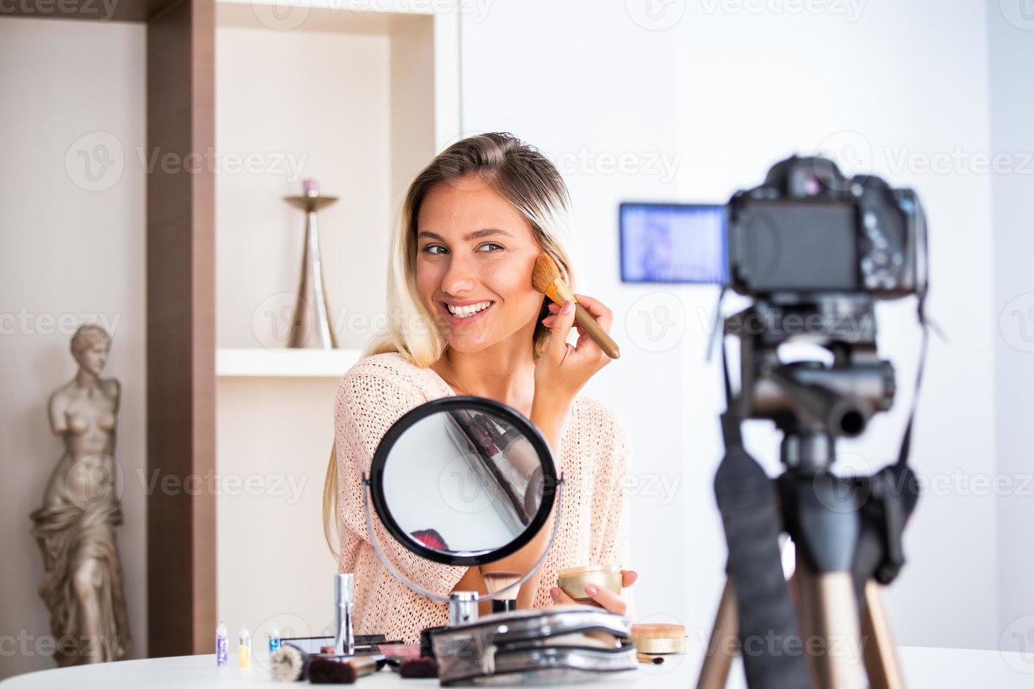 joven hermosa mujer rubia vlogger de belleza profesional o blogger grabando tutorial de maquillaje para compartir en las redes sociales foto