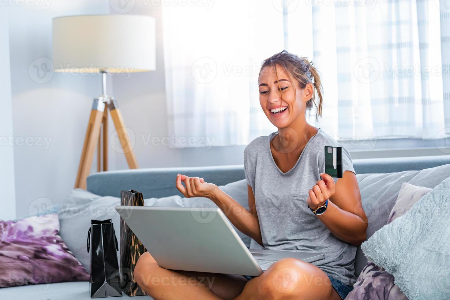 mujer joven con tarjeta de crédito y usando computadora portátil. concepto de compras en línea. mujer feliz haciendo compras en línea en casa foto