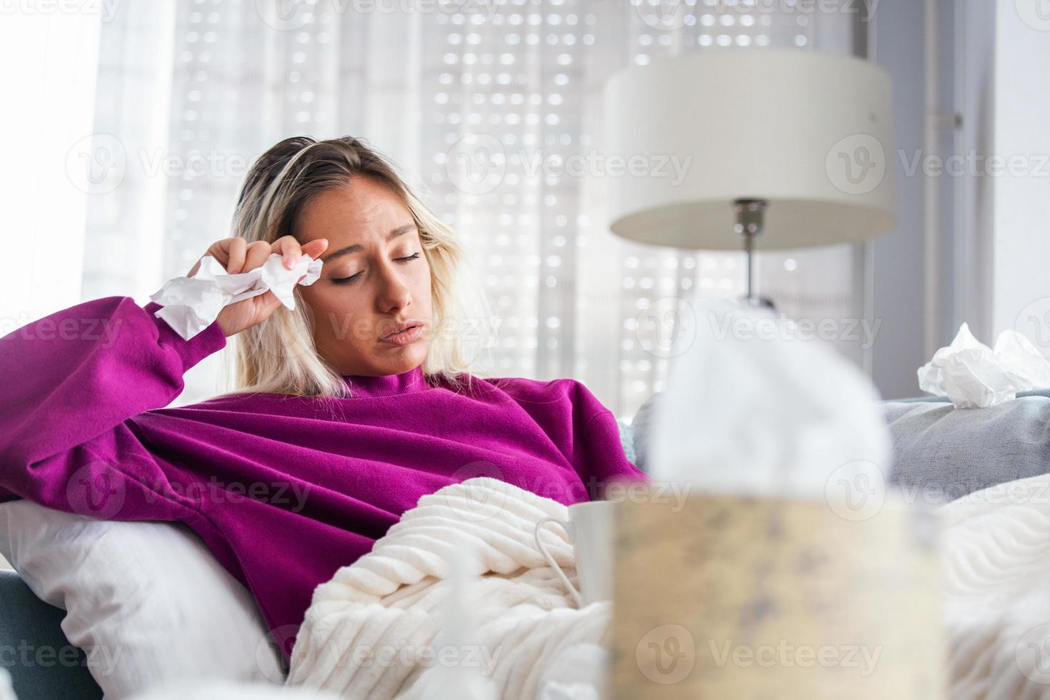 una mujer enferma y desesperada tiene gripe. rinitis, resfriado, enfermedad, concepto de alergia. una mujer bastante enferma tiene secreción nasal, se frota la nariz con un pañuelo. mujer estornudando. morena estornudando en un pañuelo foto
