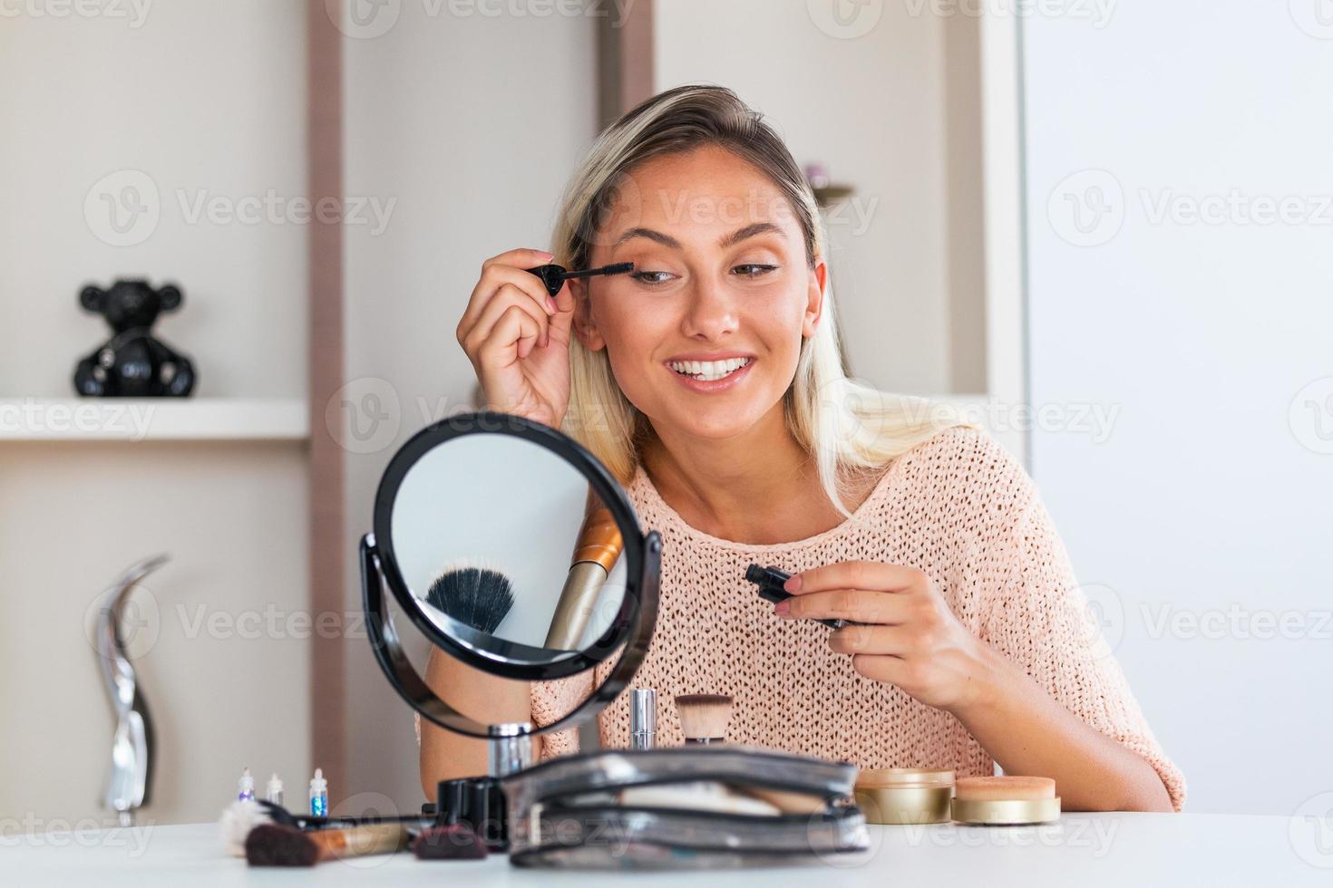 mujer aplicando rímel negro en las pestañas con pincel de maquillaje. maquillaje de belleza. retrato de una hermosa joven aplicando rímel negro en las pestañas, sosteniendo un cepillo en la mano. foto