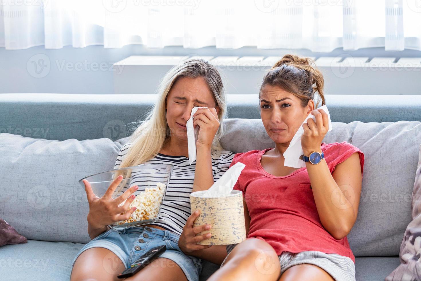 Sad girls watching a movie Crying for a touching movie. two best friends watch sad movie at home in bed crying touching. photo