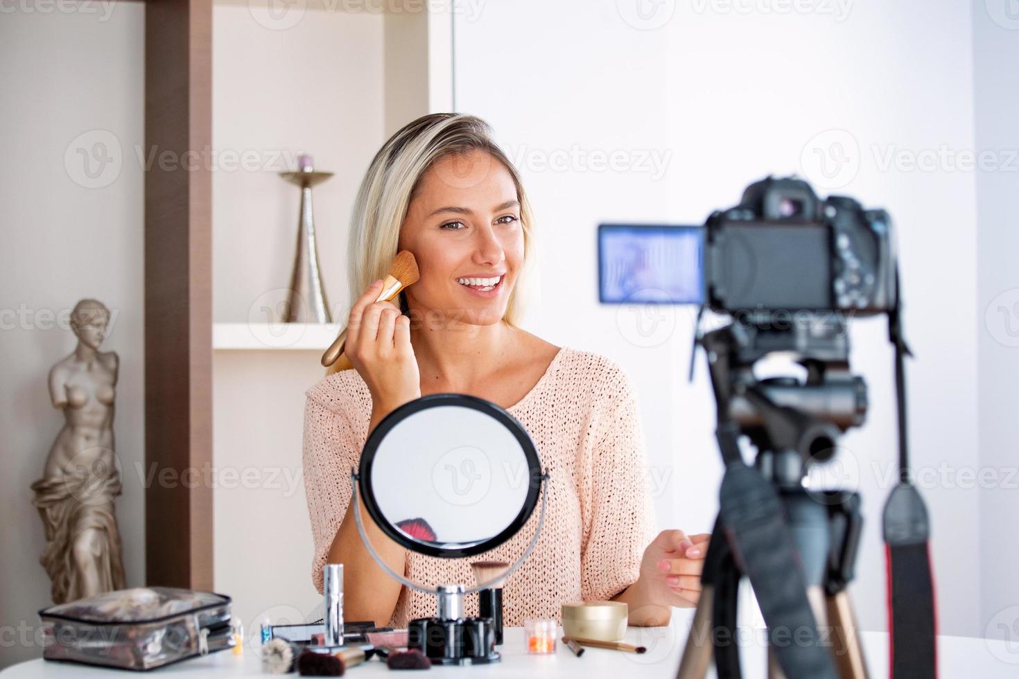 Young beautiful blonde woman professional beauty vlogger or blogger recording make up tutorial to share on social media photo