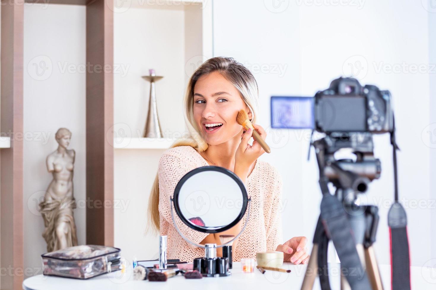 Young beautiful blonde woman professional beauty vlogger or blogger recording make up tutorial to share on social media photo