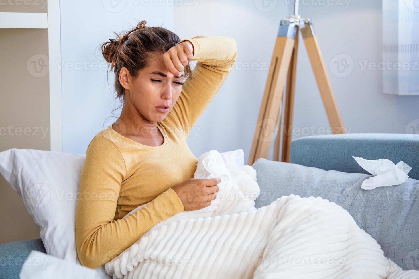 mujer enferma con dolor de cabeza sentada debajo de la manta. mujer enferma con infecciones estacionales, gripe, alergia acostada en la cama. mujer enferma cubierta con una manta acostada en la cama con fiebre alta y gripe, descansando. foto