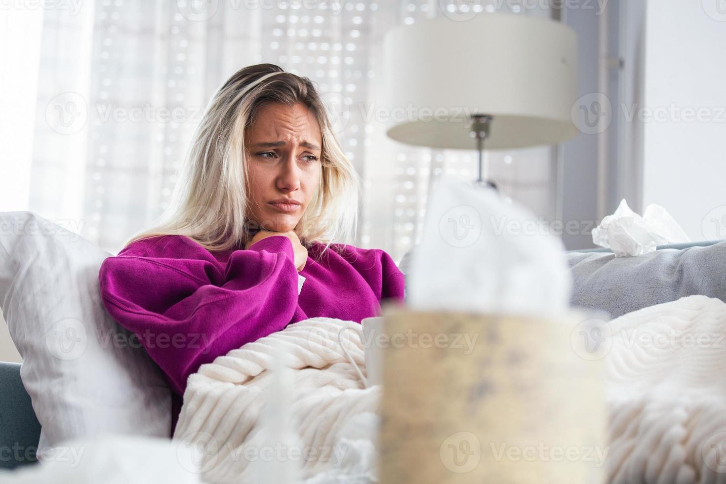 Sick desperate woman has flu. Rhinitis, cold, sickness, allergy concept. Pretty sick woman has runnning nose, rubs nose with handkerchief. Sneezing female. Brunette sneezing in a tissue photo