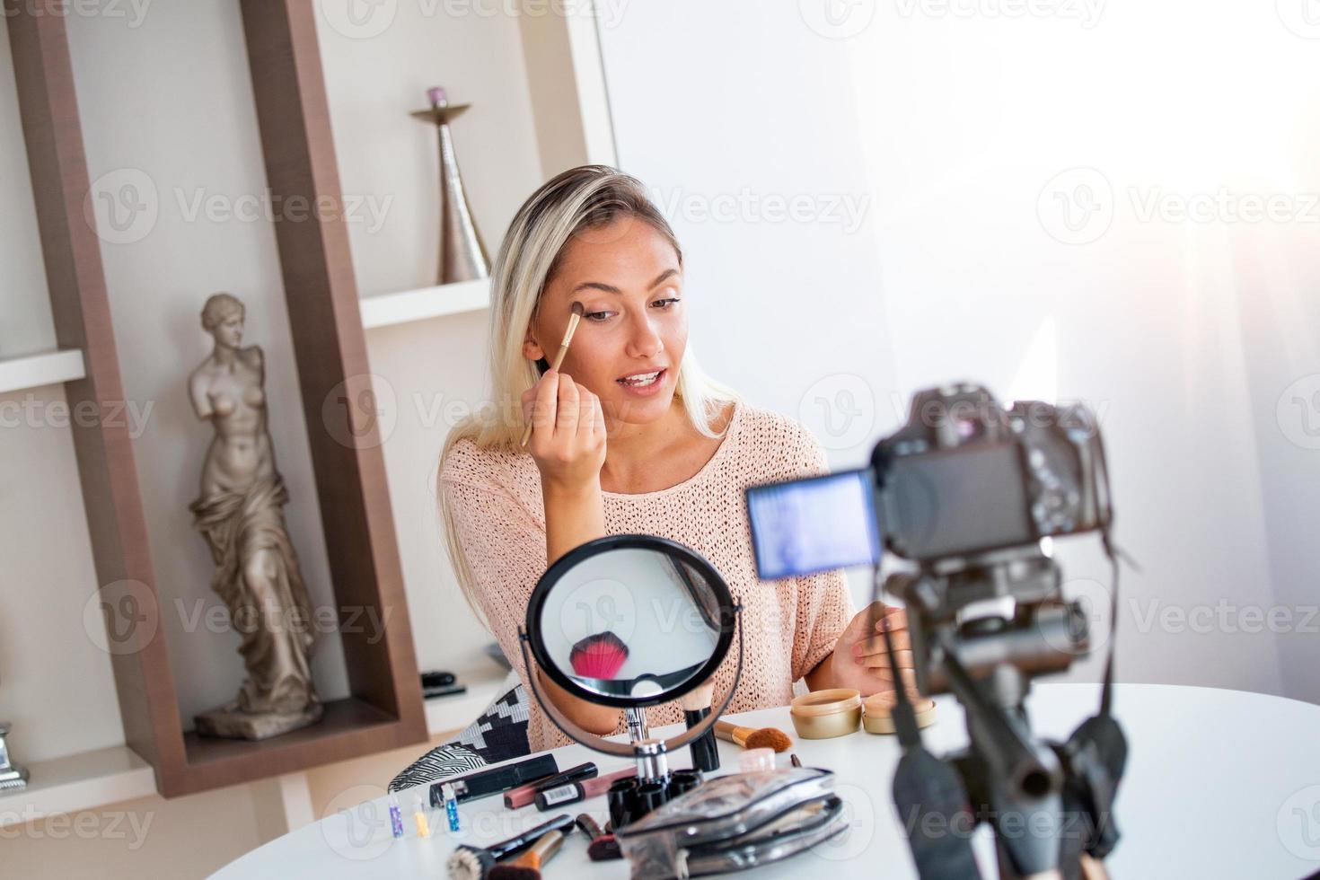 Young beautiful blonde woman professional beauty vlogger or blogger recording make up tutorial to share on social media photo