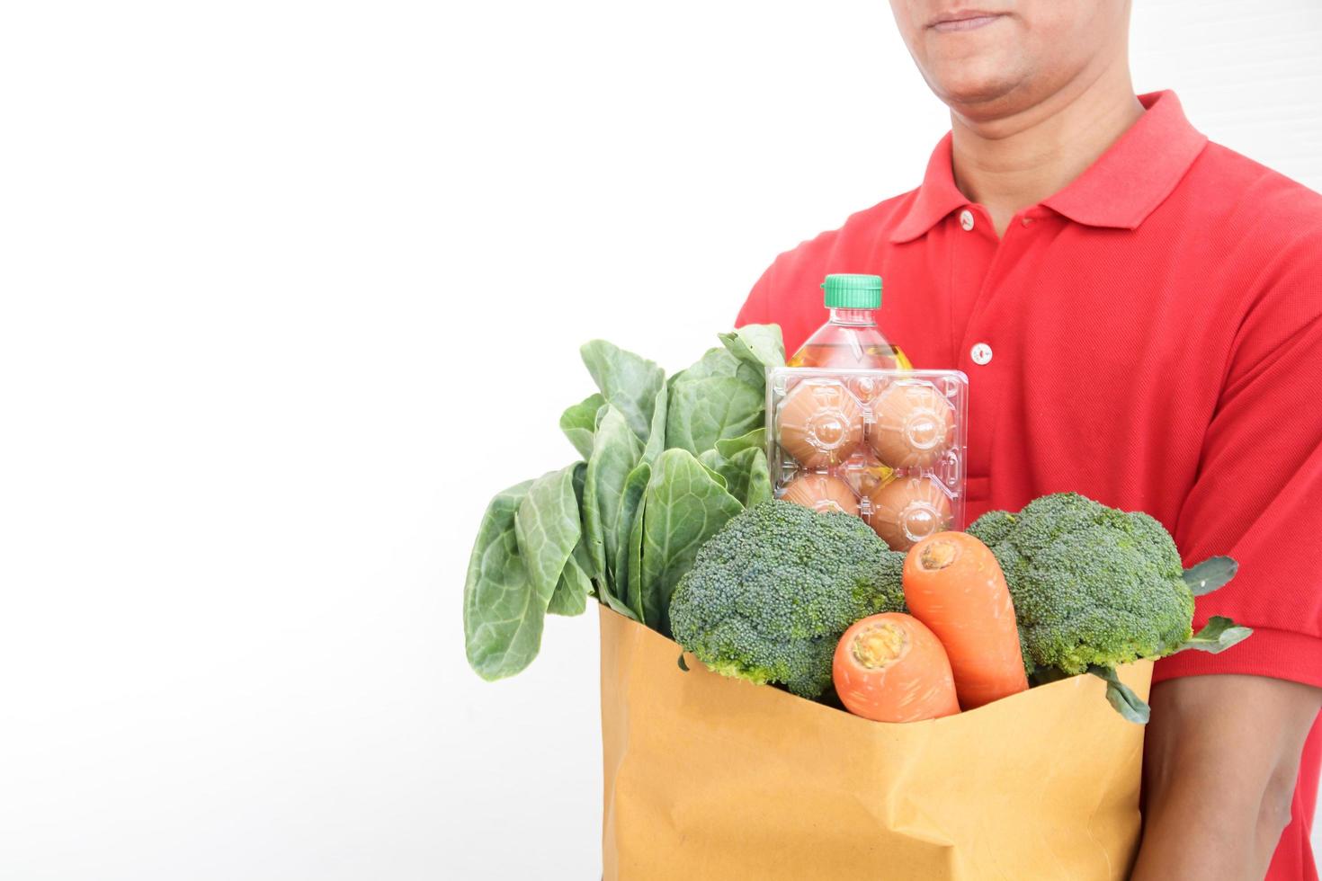 Asian delivery man wearing a mask holds food, eggs, vegetables, ingredients Delivered to the customer. Business concept of food delivery service Buy online during the coronavirus. Copy space photo