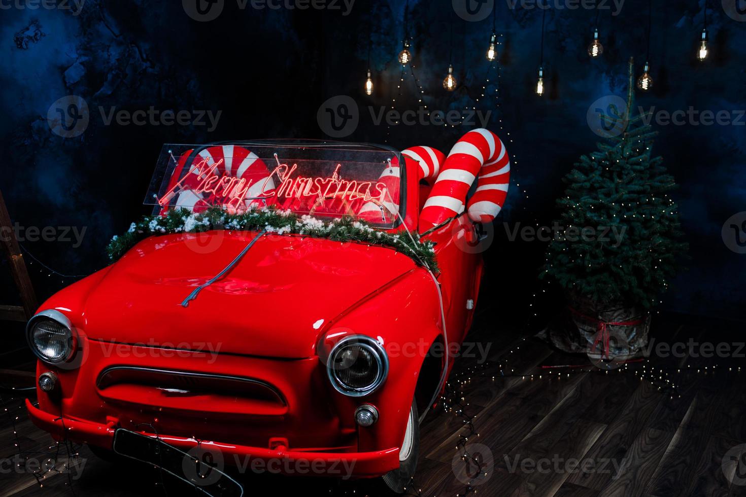 tro red car with led red inscription merry christmas on it. big christmas lollipops in the car in studio background photo