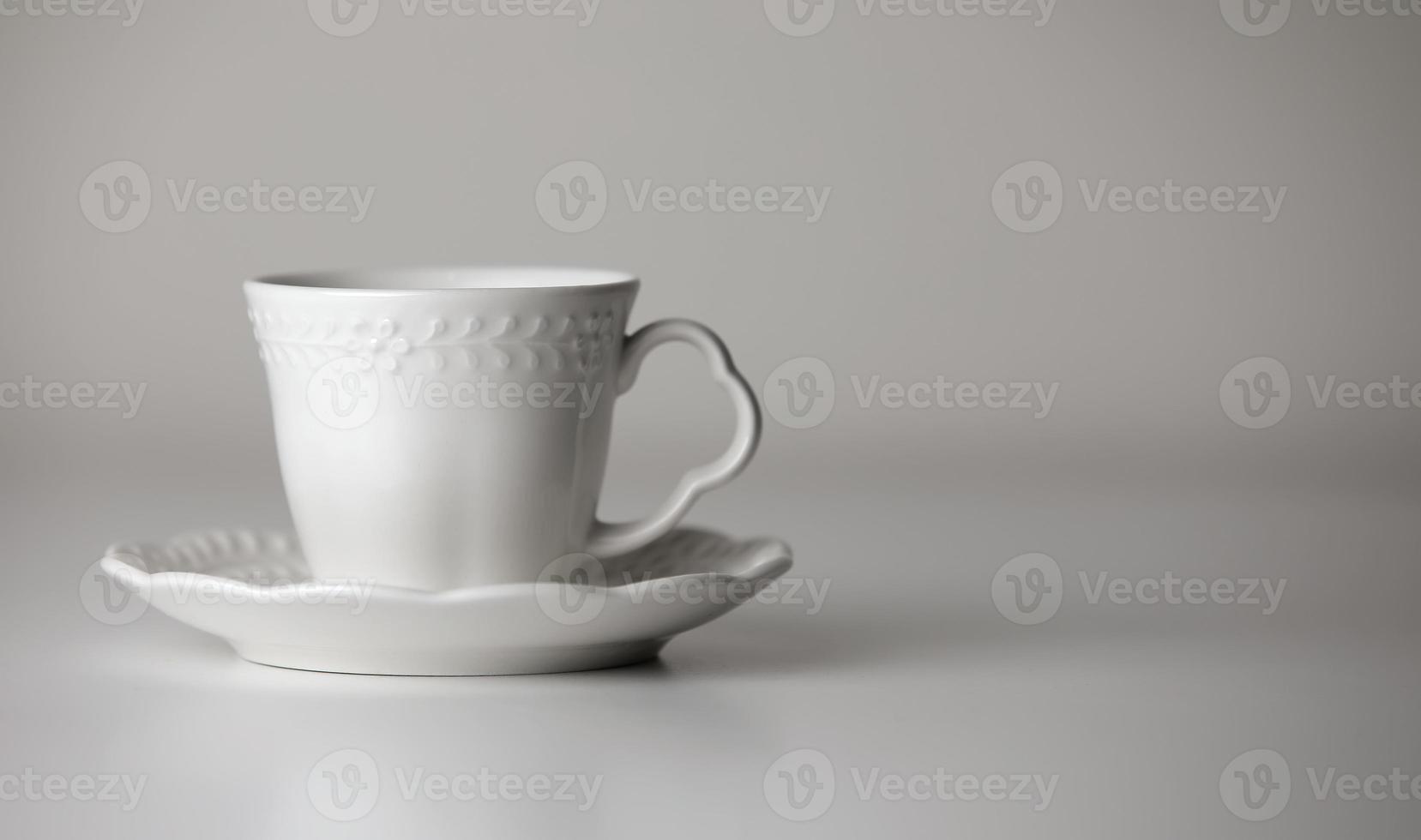 White tea cup and saucer with a pattern for drink on white background. Ceramic coffee cup or mug close up. Mockup classic porcelain utensils. copy space photo