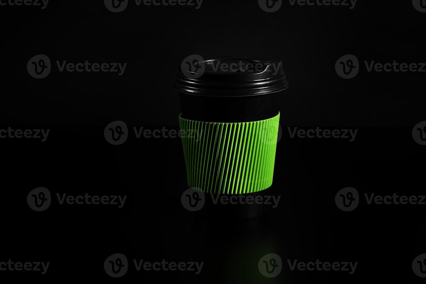 a glass of hot tea or coffee. Black paper glass with a lid on a black background. side view photo