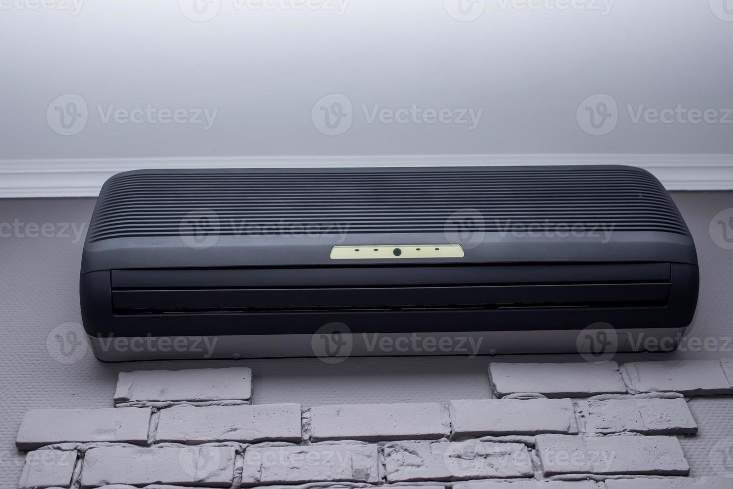 modern black air conditioner hanging on white brick wall. High quality photo