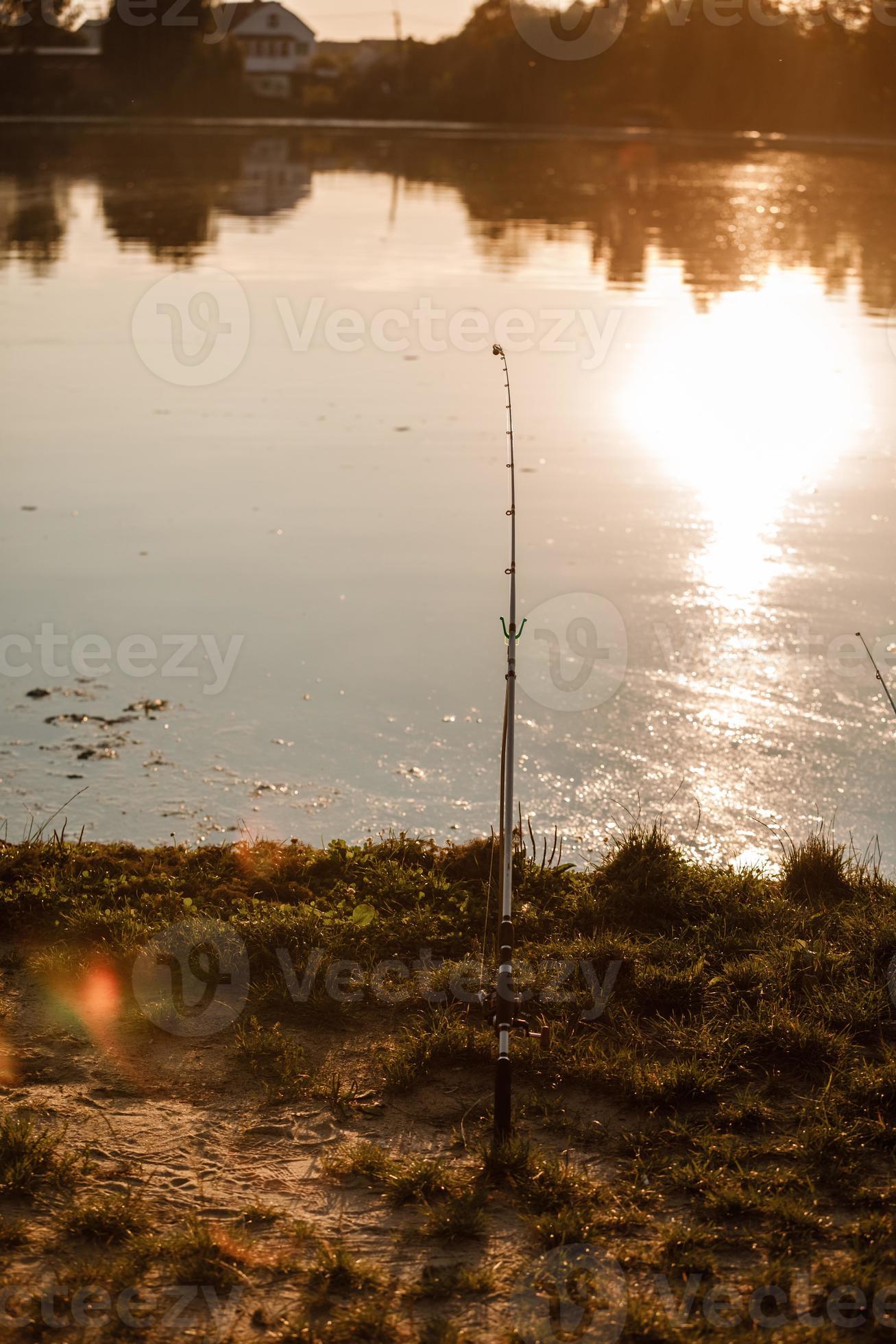 Fisherman with rod, spinning reel on the river bank. Fishing for