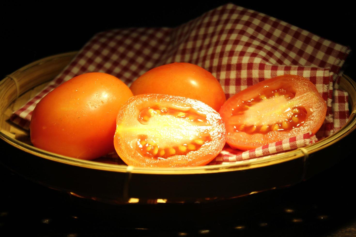fresh red tomatoes with on wooden background and water droplets on a dark moody photo