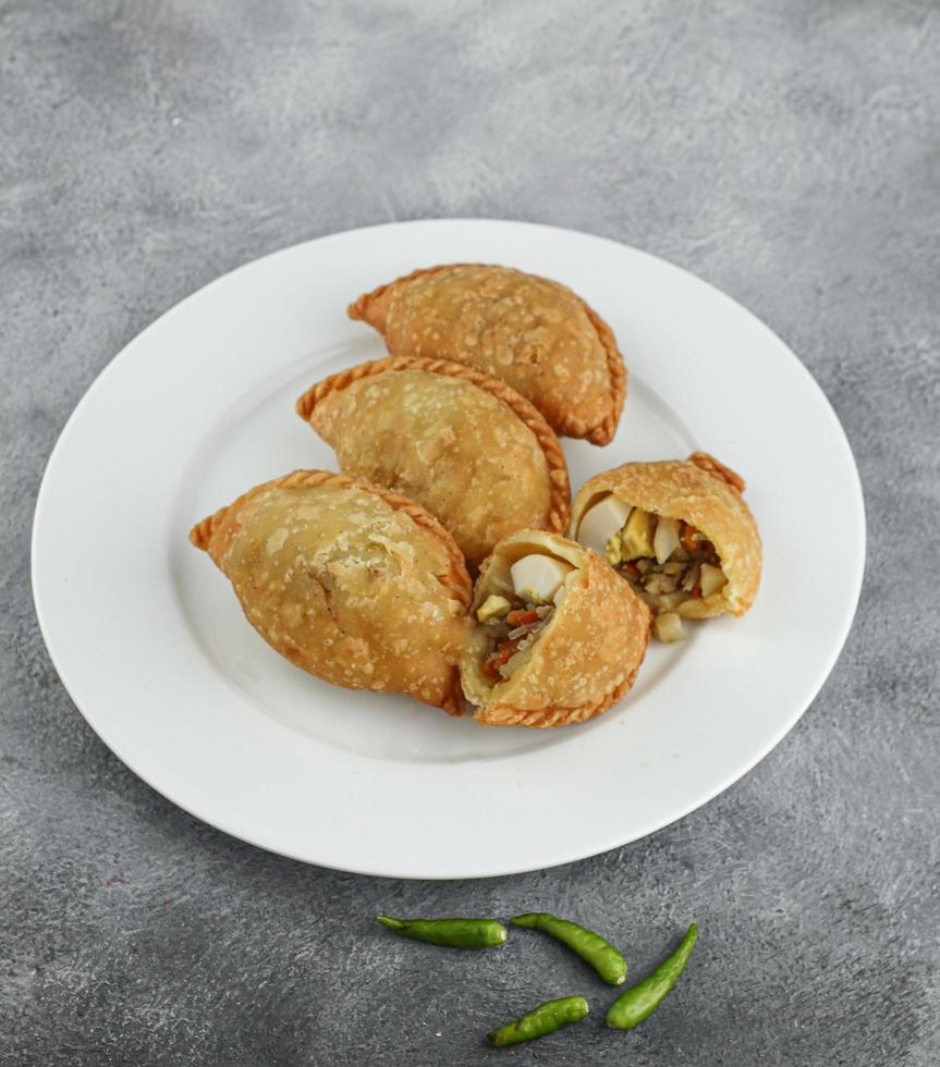 Kue pastel, traditional savory snack from Indonesia filled with carrots, potatoes and egg, eat with chili or sauce. Selective focus photo