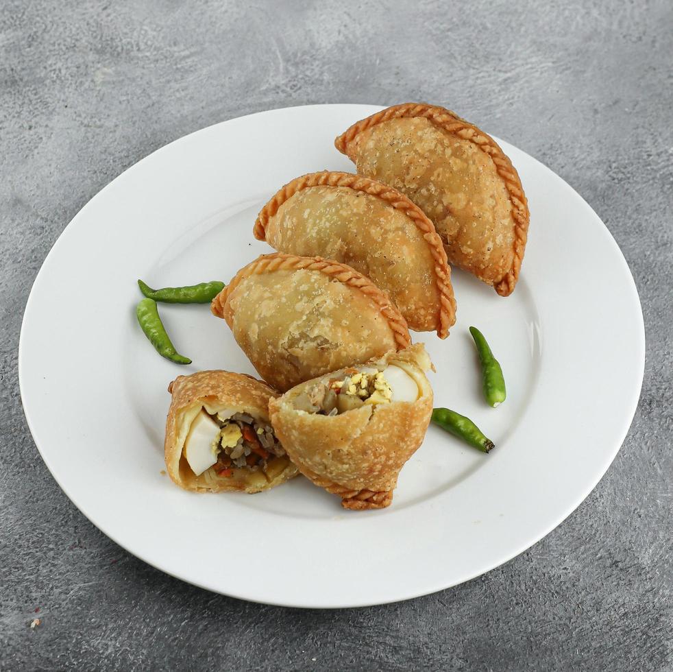 Kue pastel, traditional savory snack from Indonesia filled with carrots, potatoes and egg, eat with chili or sauce. Selective focus photo