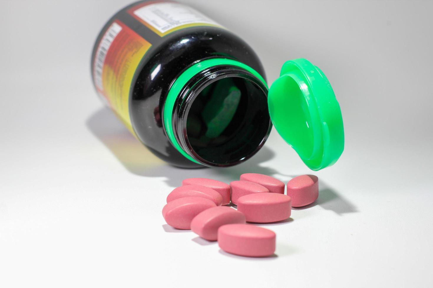 Tablets pills round out of container on white background selective focus photo