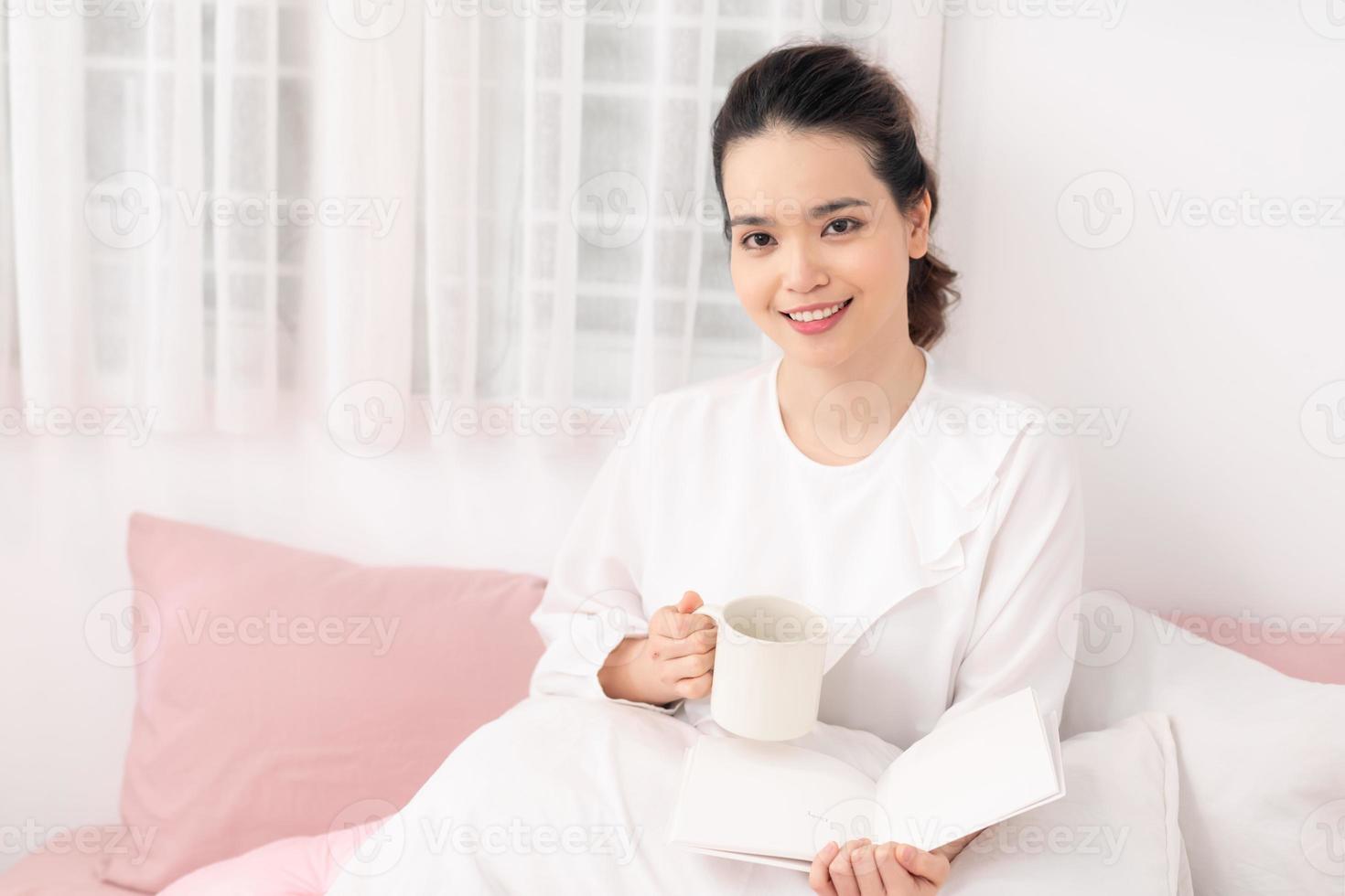 Beautiful woman reading a book on the bed in the morning photo