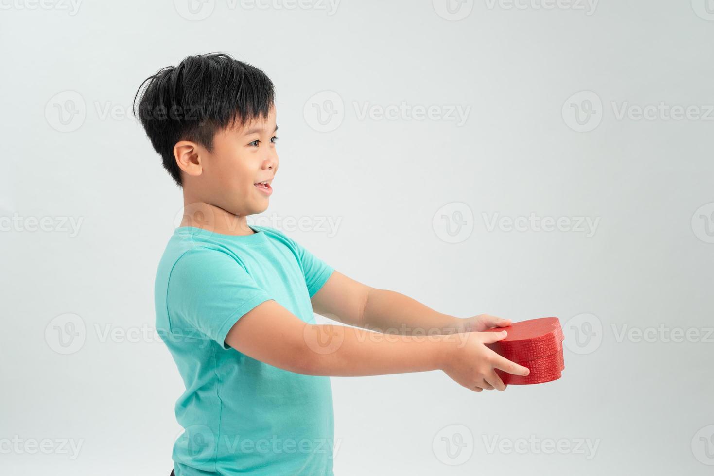 Cute boy holding heart shaped box on white background photo