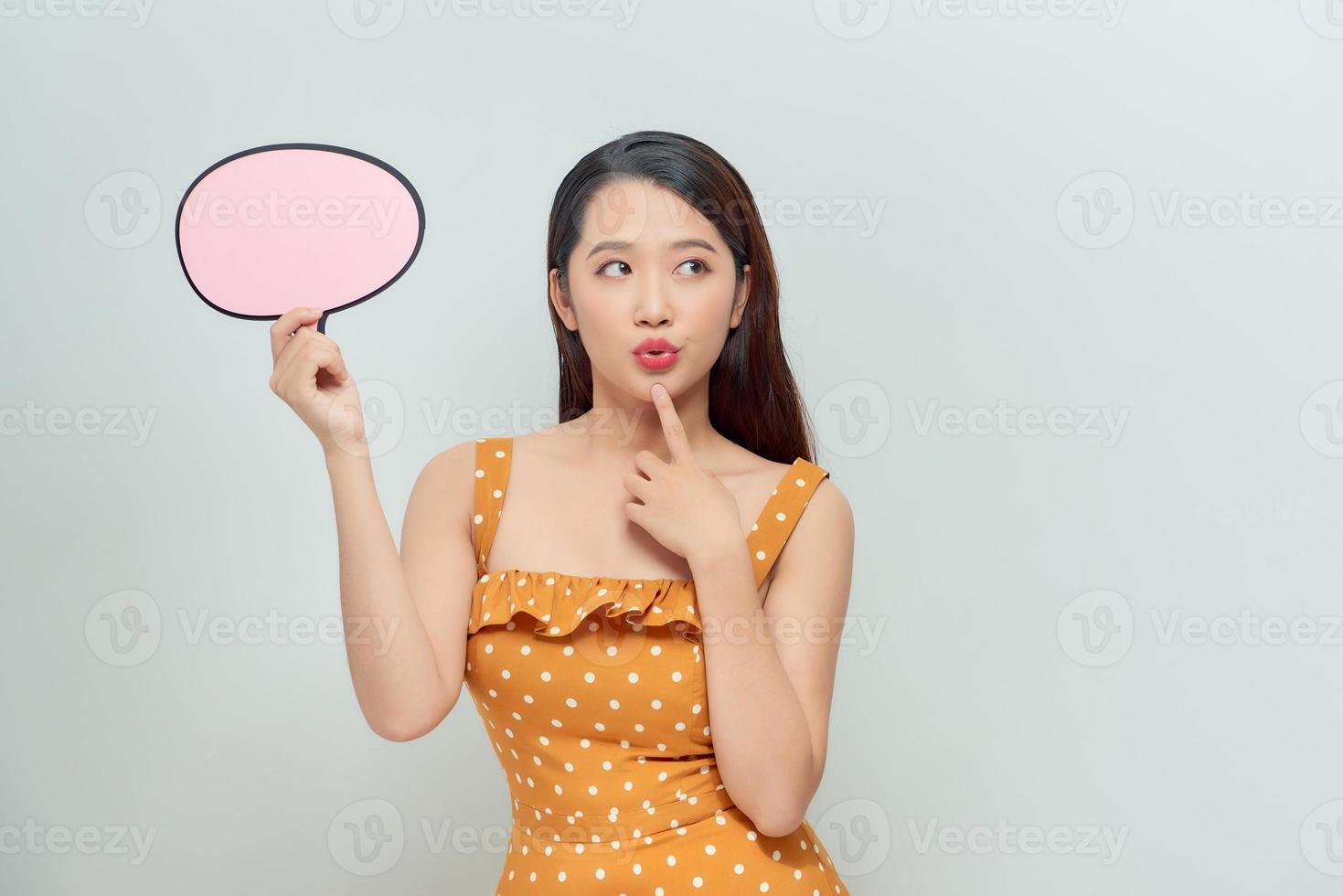 Happy woman holding blank speech bubble over bright background photo