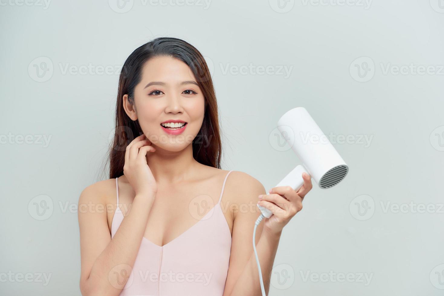 Smiling young woman singing while blow-dry photo