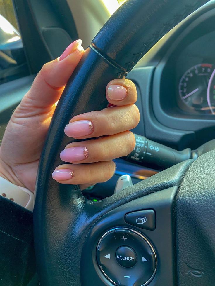 female hands demonstrating fresh manicure hold the steering wheel of a honda car photo