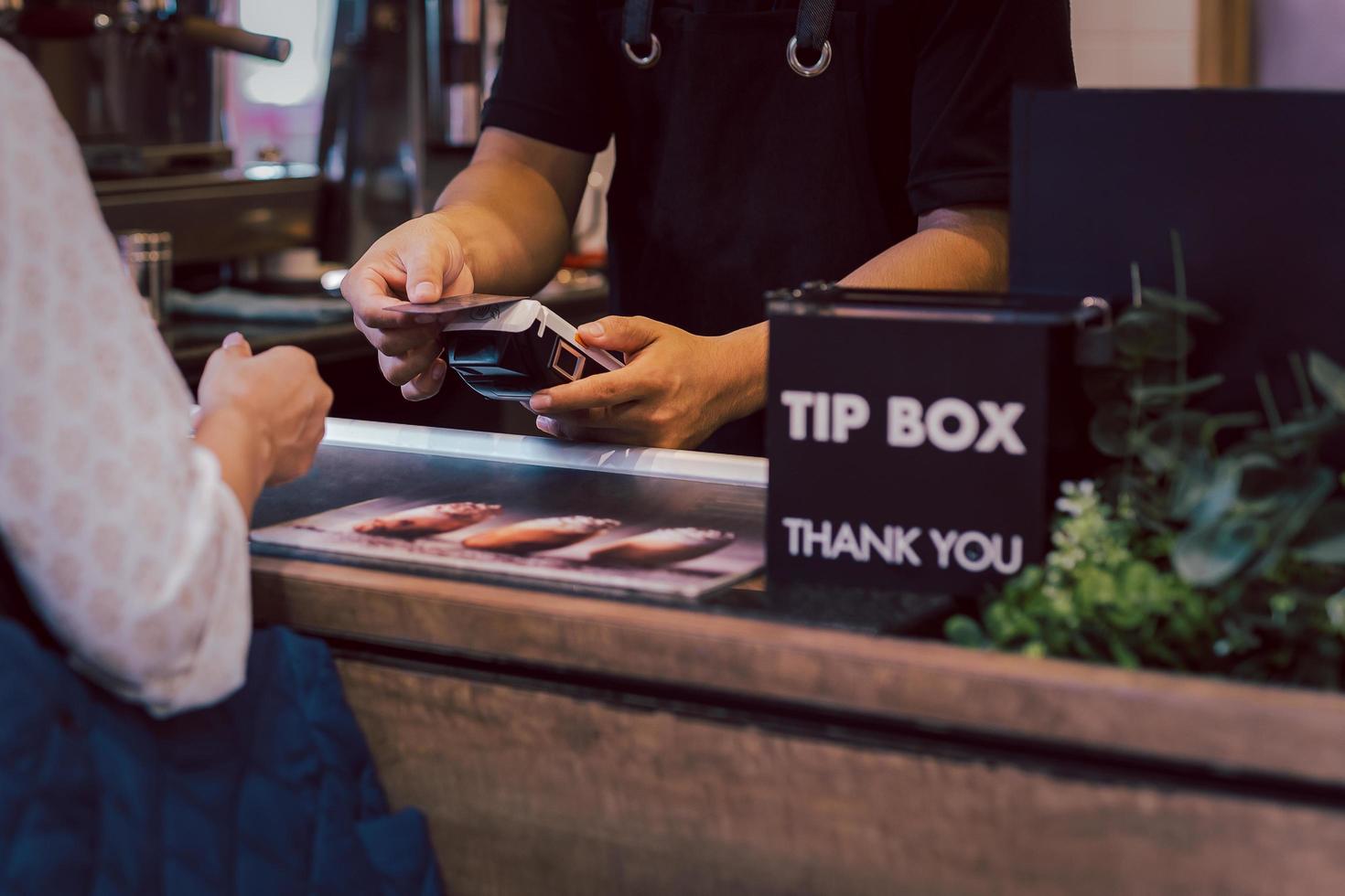 Asia woman use cashless wifi paywave scan on card reader in coffee shop. photo