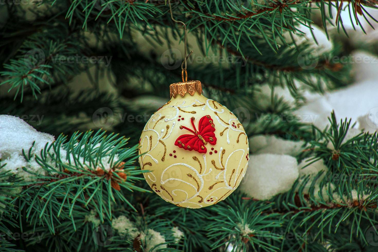 Christmas ball hanging on a snow-covered branch of a Christmas tree on a festive background of white snow and snowy bokeh with copy space photo