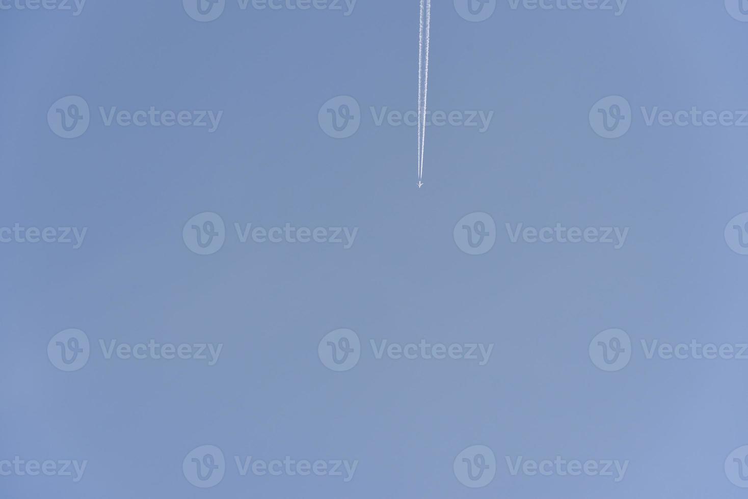 The contrail of an airplane in the blue sky. The flight of a passenger plane. photo