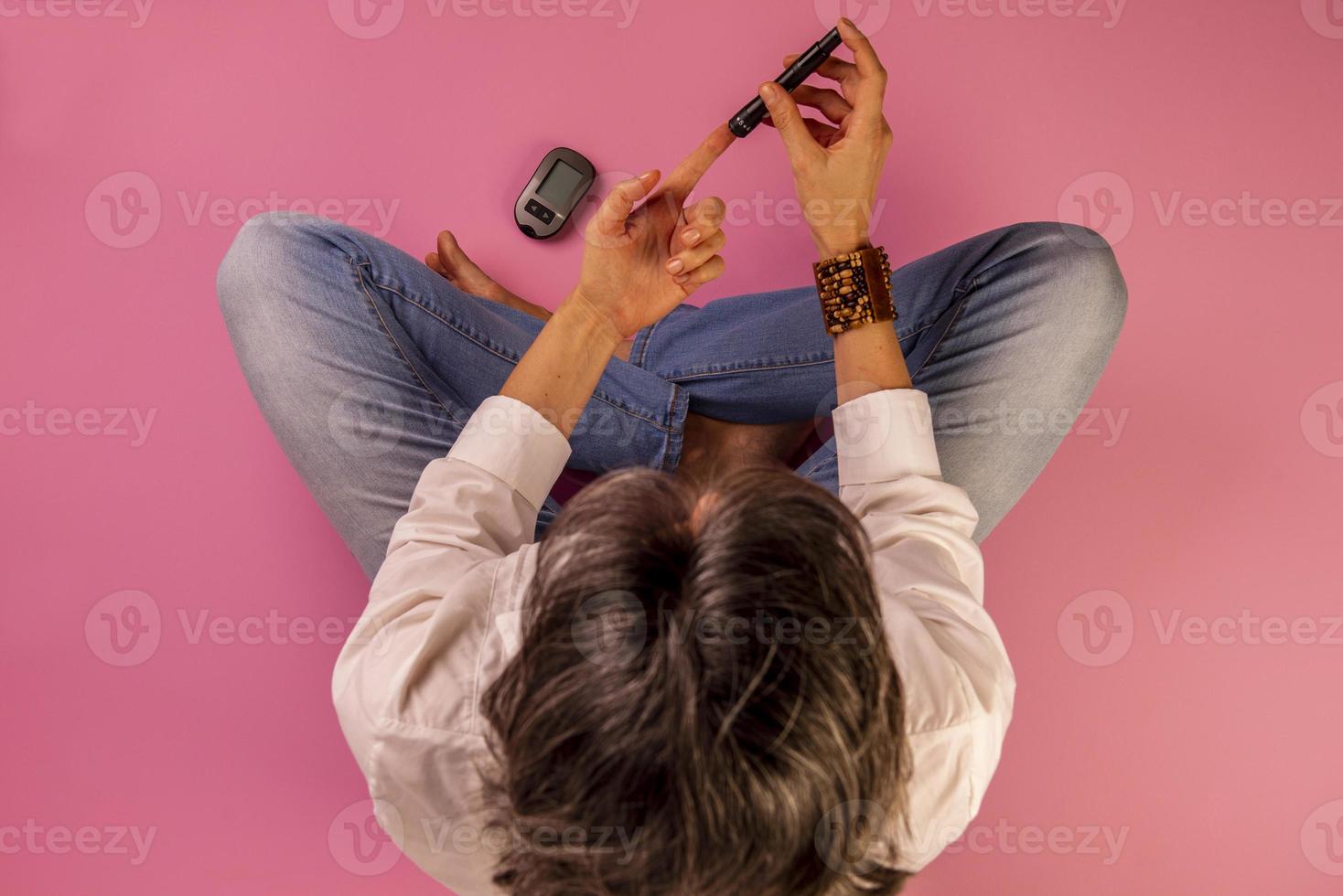 diabetic woman sitting on the floor using devices to measure blood glucose photo