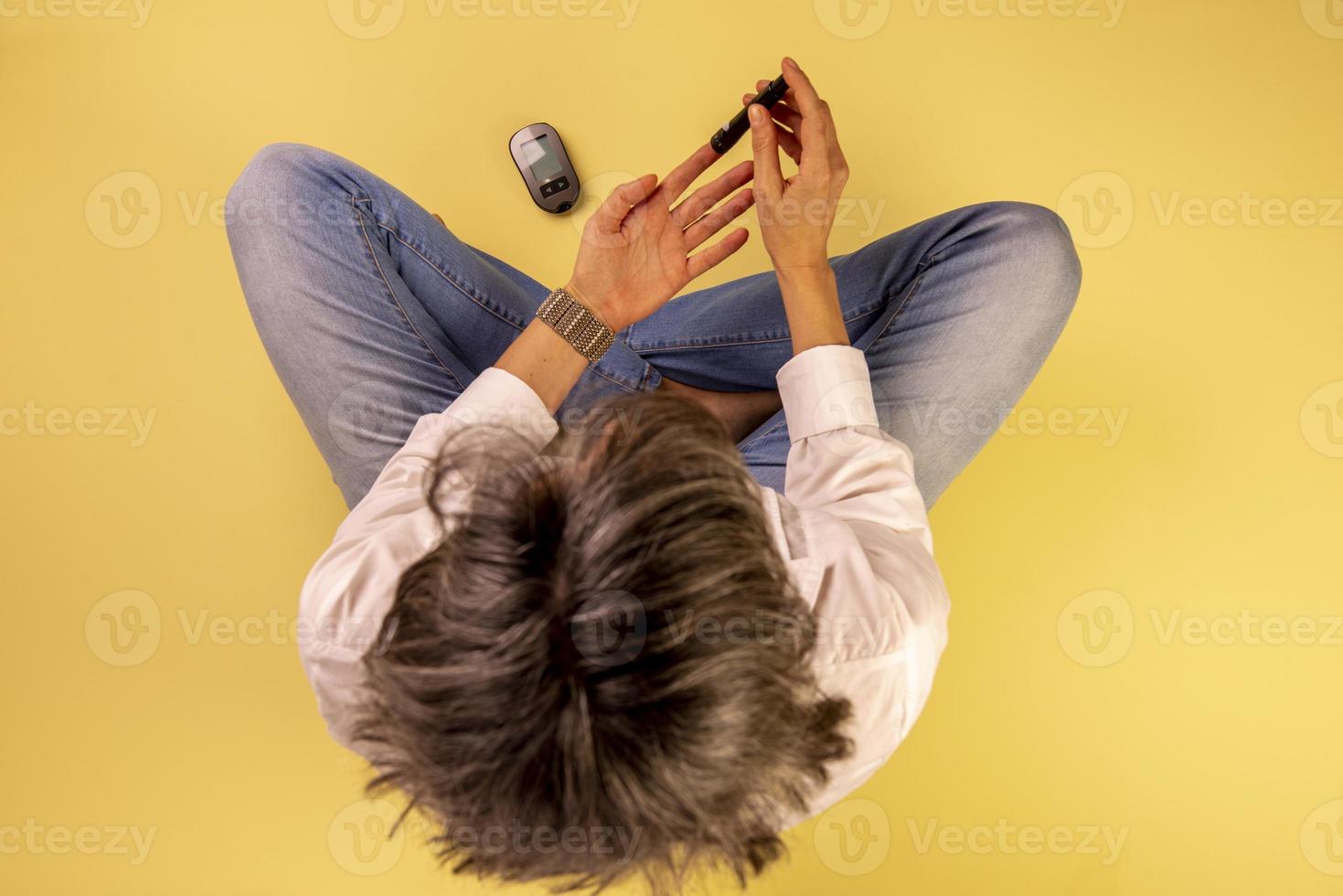 mujer diabética sentada en el suelo usando dispositivos para medir la glucosa en sangre foto