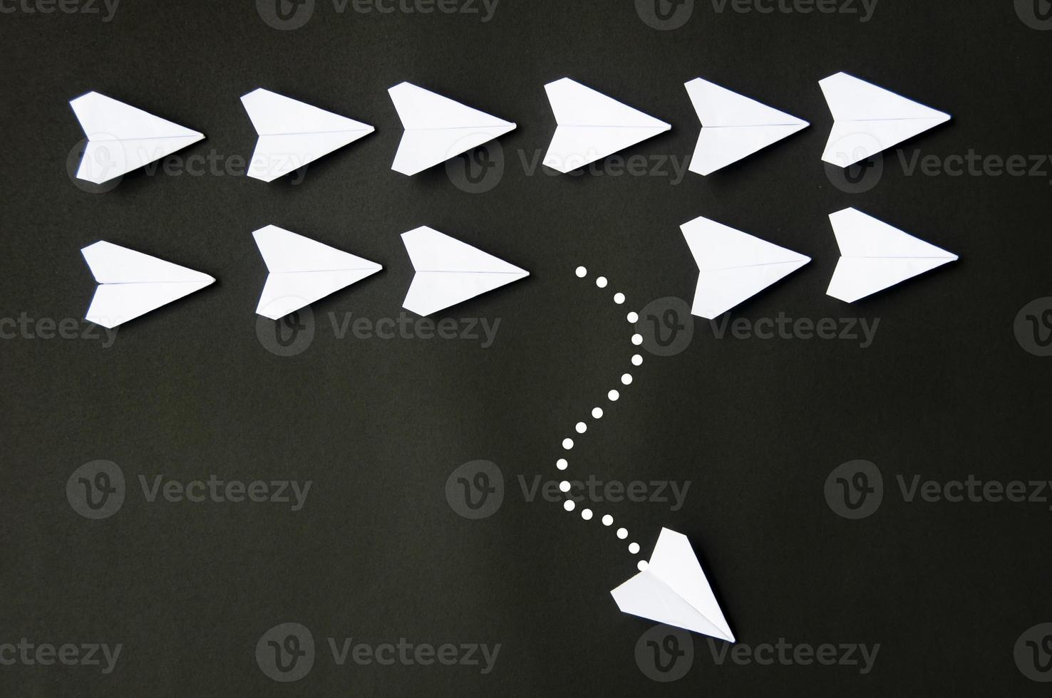 White paper plane origami leaving other white planes on dark background. Leadership skills concept photo