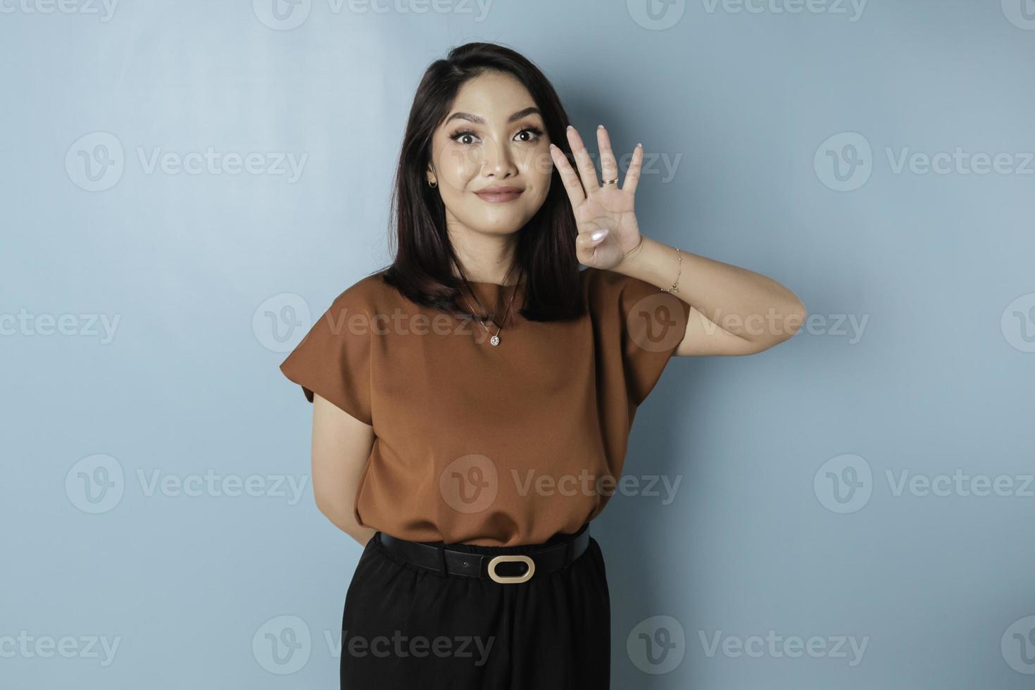 Excited Asian woman wearing a brown t-shirt giving number 12345 by hand gesture photo
