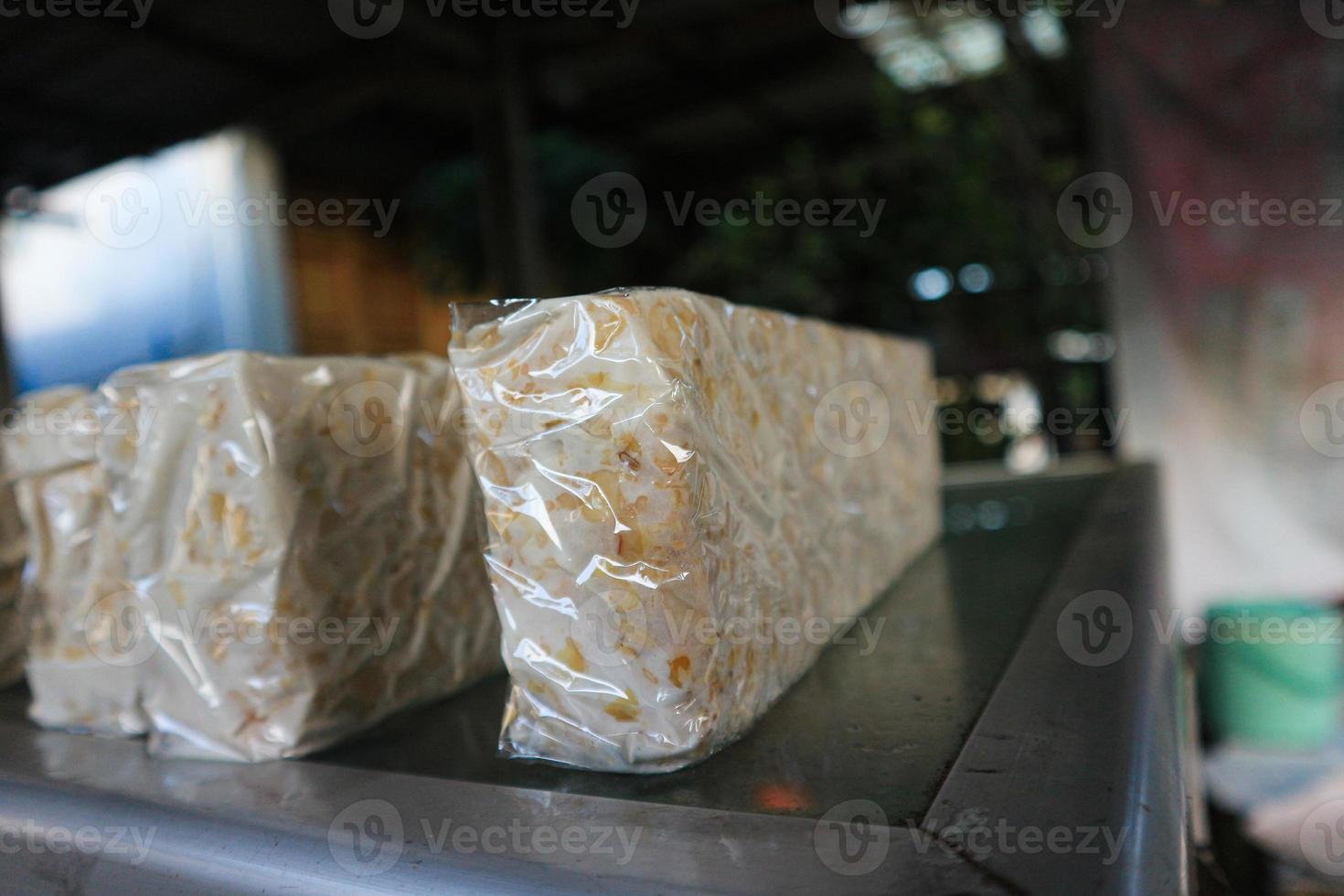 tempe or tempeh wrapped in transparant plastic or smoetimes banana leaves,is a indonesian traditional food.made of fermented soya beans. photo