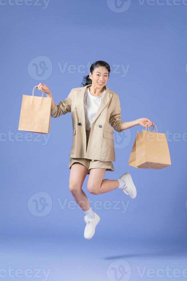 Happy young woman with shopping bags on purple background photo