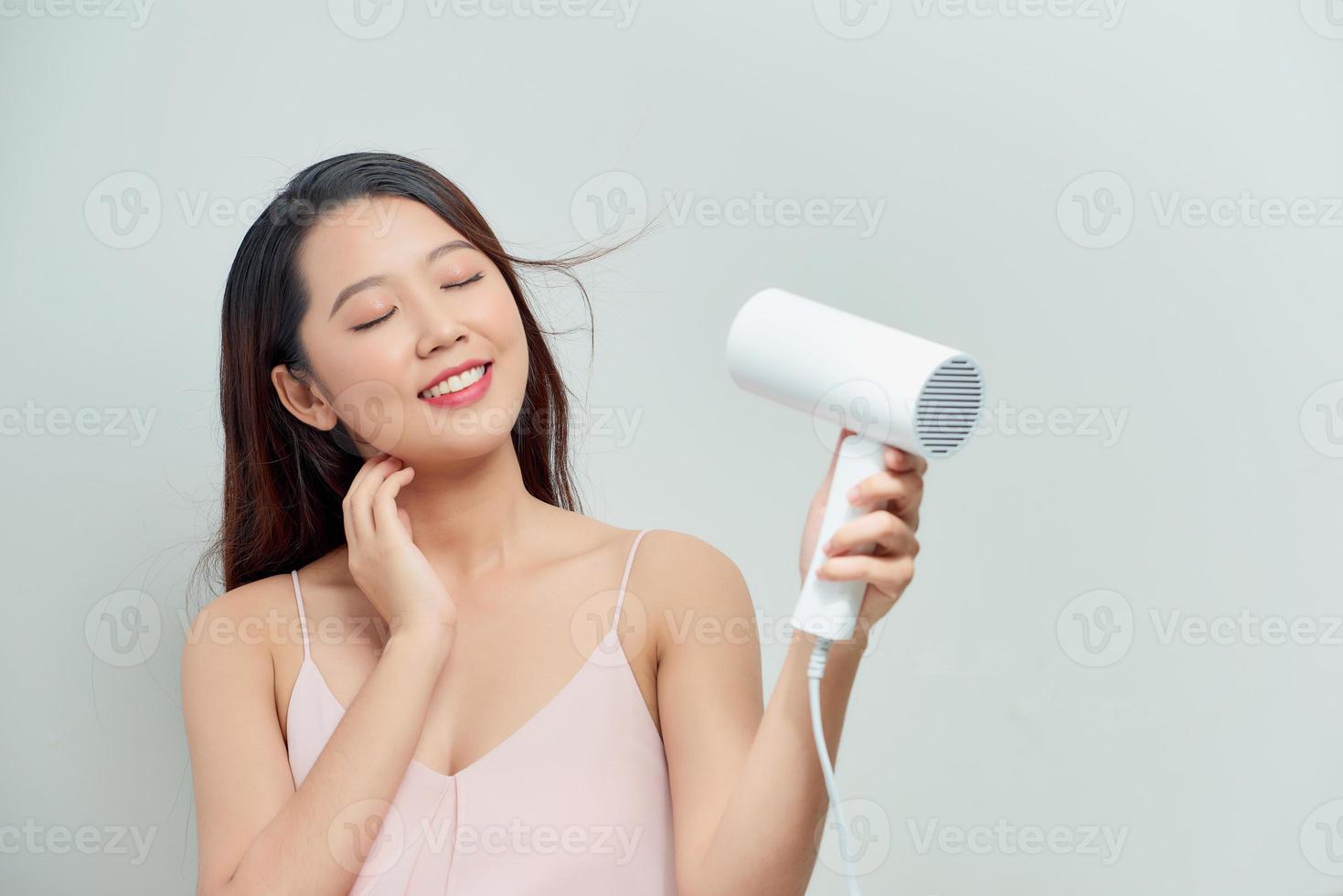 mujer joven secando su hermoso cabello con secador de pelo foto