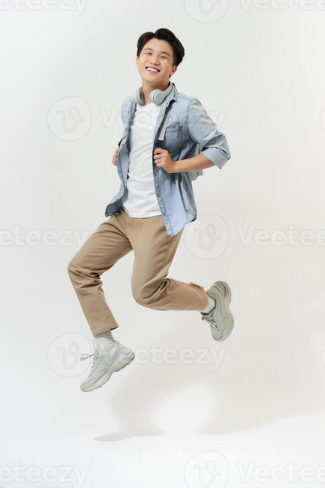 estudiante asiático saltando con mochila aislado en blanco foto